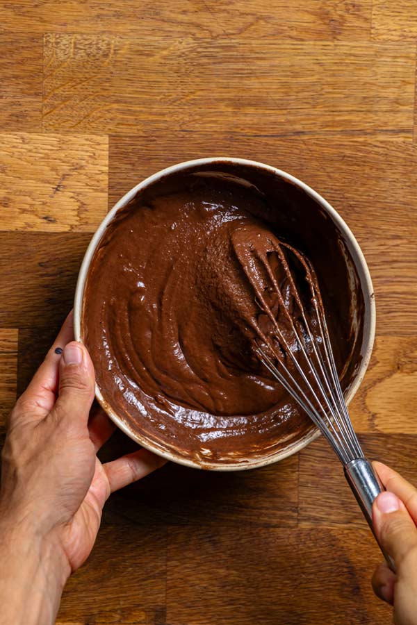 fertiges biskuitteig fuer gesundes tiramisu von oben in einer schuessel mit zwei haenden und einem schneebesen