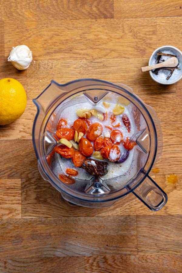 alle zutaten fuer vegane tomatensuppe in einem mixer von oben auf einem holztisch mit deko