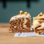 zimtschneckenkuchen von vorne mit einem herausgeschnittenen stück mit sichtbaren marmorierungen auf einem holztisch