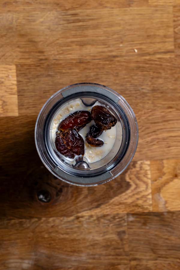 zutaten fuer dattelmilch von oben in einem mixbehaelter auf einem holztisch