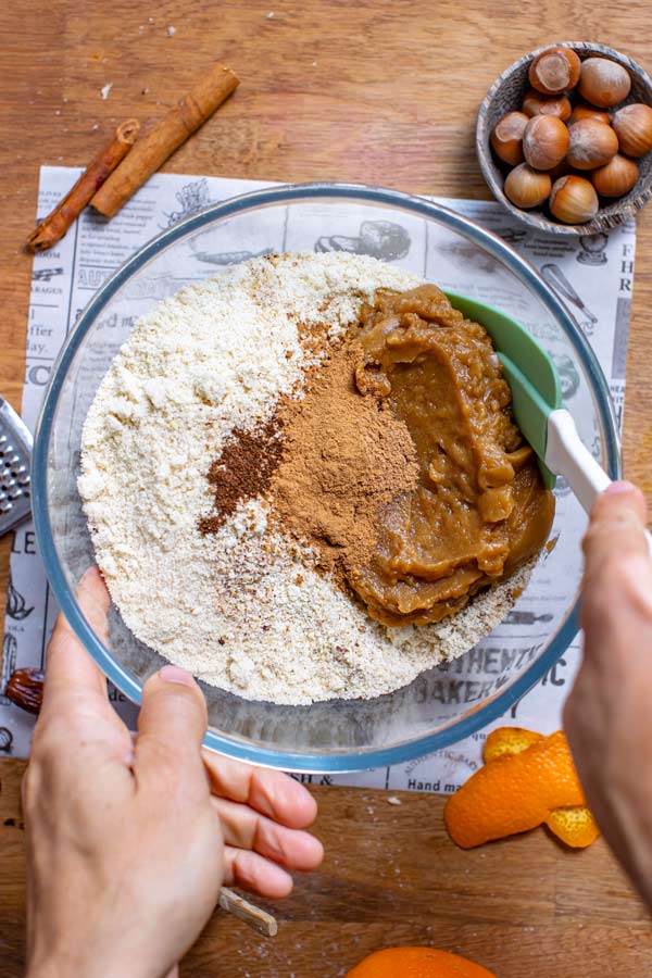 alle zutaten fuer zimtsterne in glasschuessel von oben mit zwei haenden und spatula