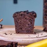 schoko zucchini kuchen angeschnitten auf holzbrett von vorne mit deko
