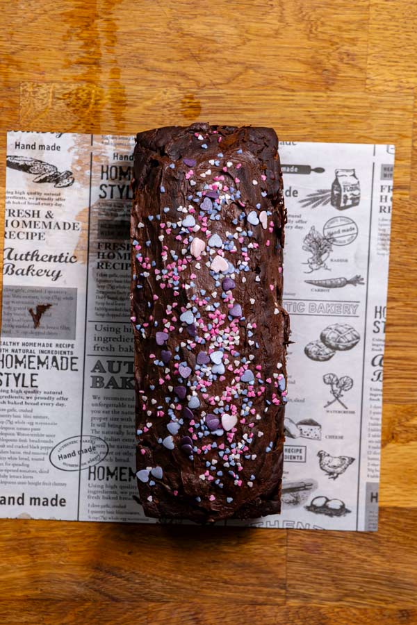 fertig gebackener kuchen mit zucchini am stueck von oben auf backpapier mit bunten streuseln