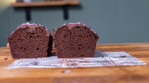 kuchen mit zucchini halbiert von vorne auf einem holztisch auf weissem backpapier