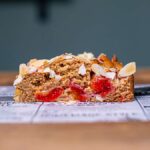 stueck zwetschgenkuchen von vorne auf weissem backpapier auf holztisch