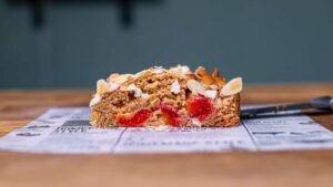stueck zwetschgenkuchen von vorne auf weissem backpapier auf holztisch