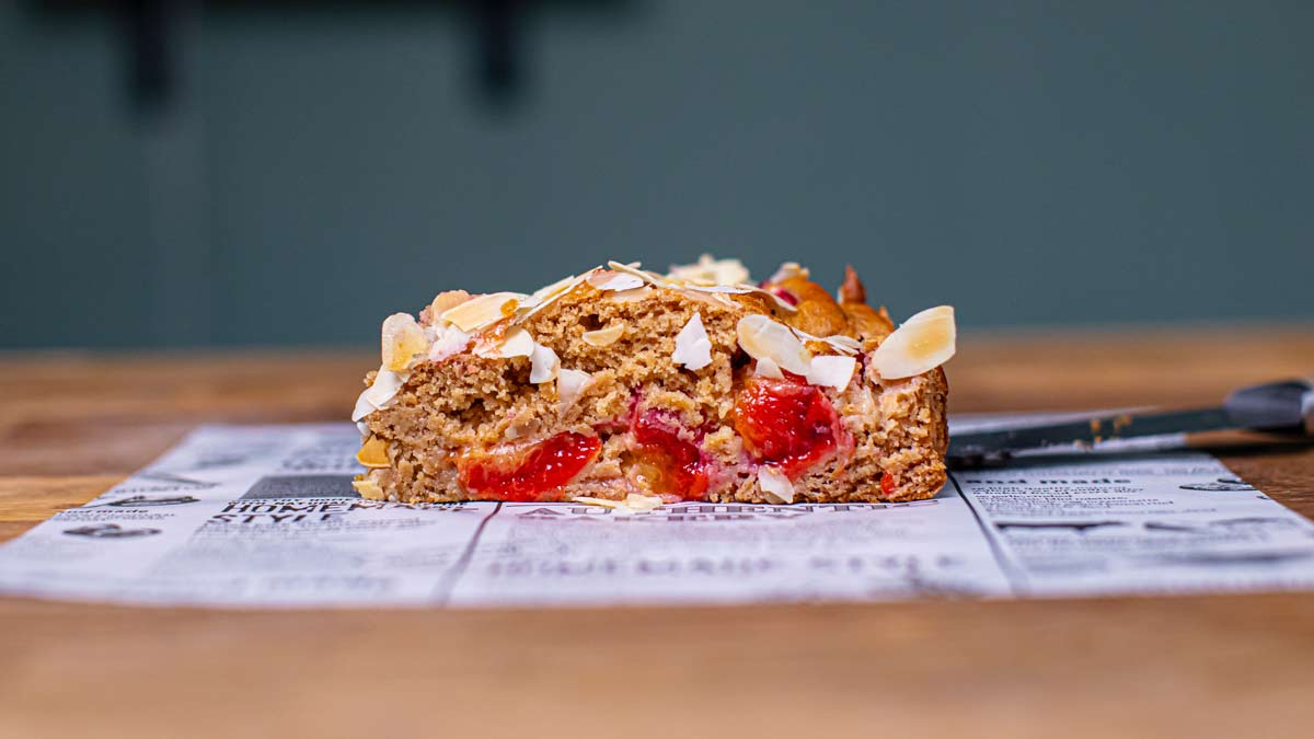 stueck zwetschgenkuchen von vorne auf weissem backpapier auf holztisch