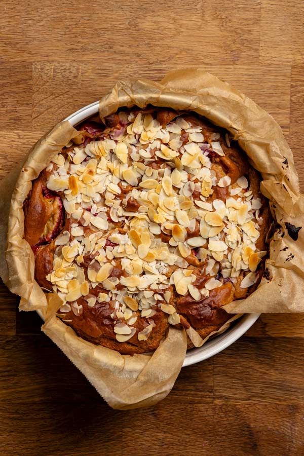 gebackener kuchen mit zwetschgen in der springform von oben auf einem holztisch